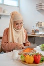 A happy Asian Muslim woman or housewife is preparing food, cooking her healthy salad mix Royalty Free Stock Photo