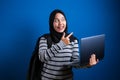 Happy Asian muslim woman smiling at camera while holding laptop Royalty Free Stock Photo