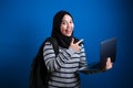 Happy Asian muslim woman smiling at camera while holding laptop Royalty Free Stock Photo