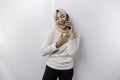 A happy Asian Muslim woman wearing a headscarf, holding her phone, isolated by white background Royalty Free Stock Photo