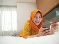 Happy Asian muslim woman wearing hijab smiling and laughing, when making purchase on online shop with her phone and credit card Royalty Free Stock Photo