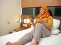 Happy Asian muslim woman wearing hijab smiling and laughing, when making purchase on online shop with her phone and credit card Royalty Free Stock Photo