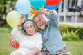 Happy asian old couple holding balloons in the front lawn at home. senior man and elder woman Spend time together in backyard . Royalty Free Stock Photo