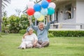 Happy asian old couple holding balloons in the front lawn at home. senior man and elder woman Spend time together in backyard . Royalty Free Stock Photo