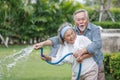 happy asian old couple watering the plants in the front lawn at home. senior man and elder woman Spend time together in backyard Royalty Free Stock Photo