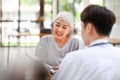 A happy Asian old lady is talking about health treatments and being checked on by a doctor Royalty Free Stock Photo