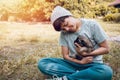 Happy Asian owner carrying, hugging adorable puppy dog on her sitting green grass backyard lawn Royalty Free Stock Photo