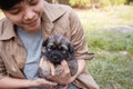 Happy Asian owner carrying, hugging Carrying adorable puppies dog her sitting green grass backyard lawn Royalty Free Stock Photo