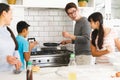 Happy asian parents with son and daughter preparing breakfast in kitchen and talking Royalty Free Stock Photo
