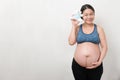 Happy Asian pregnant mother in the smiley face holding and show the little blue teddy bear, isolated on white background,