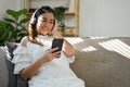 Happy Asian pregnant woman enjoys listening to music or baby`s fairy tales through headphones