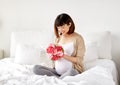 Happy asian pregnant woman with flowers in bed Royalty Free Stock Photo