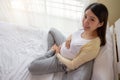 Happy Asian pregnant woman sitting on bed touching belly with care at home Royalty Free Stock Photo