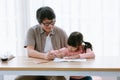 Happy Asian preschool daughter and father in glasses drawing colorful pencils while sit on desk in living room at home. Parents Royalty Free Stock Photo