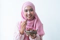 Happy Asian 30s Muslim woman wearing traditional clothes with hijab, holding a bowl of dry dates fruit in hands, smiling at camera Royalty Free Stock Photo