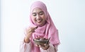 Happy Asian 30s Muslim woman wearing traditional clothes with hijab, holding a bowl of dry dates fruit, smiling looking at fruit Royalty Free Stock Photo