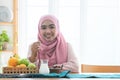 Happy Asian 30s Muslim woman wearing traditional clothes with hijab, holding dry dates fruit, looking at camera, Iftar time in Royalty Free Stock Photo