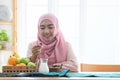 Happy Asian 30s Muslim woman wearing traditional clothes with hijab, holding and looking at dry dates fruit, Iftar time in holy Royalty Free Stock Photo