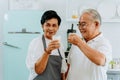 Happy Asian senior couple drinking milk at home. 70s Elderly married man and woman holding a glass of milk at kitchen Royalty Free Stock Photo