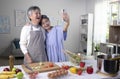 Asian senior couple looking happy while cooking and taking selfie. Royalty Free Stock Photo