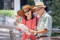 happy asian Senior couple tourists traveling looking at map and searching destination in urban city outdoors. old man Travellers