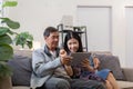 Happy Asian senior couple using digital tablet together on sofa indoor in living room. Happy retirement activity Royalty Free Stock Photo