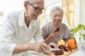 Happy asian senior grandmother cutting the fresh fruit into slices with a knife,healthy elderly people enjoy tasting delicious
