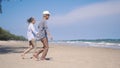 Senior man and woman couple holding hands walking to the beach sunny with bright blue sky Royalty Free Stock Photo