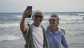 Happy Asian senior man and woman couple smile taking selfie photo with smartphone on the beach Royalty Free Stock Photo