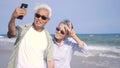 Happy Asian senior man and woman couple smile taking selfie photo with smartphone on the beach Royalty Free Stock Photo