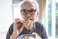 Happy asian senior woman eating chocolate chip cookie or tasting sweet cookie,natural tasty food,delicious snack,old elderly