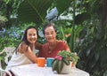 Happy Asian senior woman and her daughter  sitting together at white table in beautiful garden, daughter hugging her mother Royalty Free Stock Photo