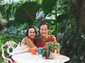 Happy Asian senior woman and her daughter  sitting together at white table in beautiful garden, daughter hugging her mother Royalty Free Stock Photo