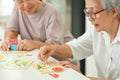 Happy asian senior woman holding picture puzzle pieces,old elderly playing a jigsaw puzzle at home,training memory and brain