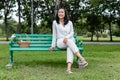 Happy asian senior woman sitting on green chair with basket apple and flower picnic in public park Royalty Free Stock Photo