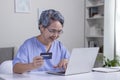 Asian senior woman using Laptop and credit card payment shopping online with customer network connection via omni channel system. Royalty Free Stock Photo