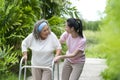 Happy Asian senior woman hard walk by walker, she living with Asian female physical therapist nurse take care Royalty Free Stock Photo