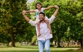 Happy asian single father carrying daughter on his shoulders in the park. Smiling man and child pretending they can fly Royalty Free Stock Photo