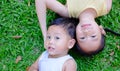 Happy asian sister and little brother lying on green grass background. Portrait of child girl and baby boy playing outdoor on lawn Royalty Free Stock Photo