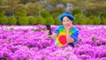 Happy Asian smiling female tourist taking selfie with smartphone while sitting in pink bougainvillea field at public park Royalty Free Stock Photo