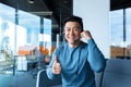 Happy asian smiling and rejoicing, businessman worker making video call, conference remotely, looking at camera and pointing Royalty Free Stock Photo