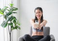 Happy Asian sports girl in sportswear sitting on chair and drinking pure milk from glass after exercise in home Royalty Free Stock Photo