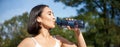 Happy asian sportswoman, runner drinks water from bottle while running, workout on fresh air in park