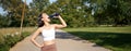 Happy asian sportswoman, runner drinks water from bottle while running, workout on fresh air in park