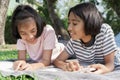 Happy Asian student while lying read book on the blanket in the summer, Asia two girl smile and relaxation together at park in the Royalty Free Stock Photo