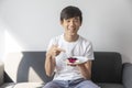 Happy Asian Teen Boy Holding Blueberry Cheesecake Cake sit on sofa at home. Royalty Free Stock Photo