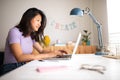 Happy asian teenage female college student doing homework at home with laptop. Royalty Free Stock Photo