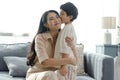 Happy Asian tender son kisses mother on mother`s day during holiday celebration at home