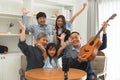 Happy Asian three generation family, grandparent, mother, father, daughter playing guitar, singing and having fun together, Royalty Free Stock Photo