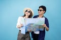 Happy Asian tourist couple opening map to travel on summer vacation isolated on blue background Royalty Free Stock Photo